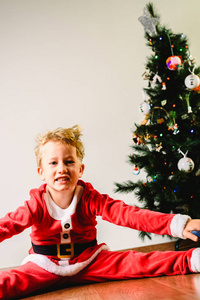 蹒跚学步的男孩，滑稽的脸，惊讶地看到圣诞老人带来礼物旁边的树表情和圣诞节的概念。