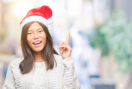 年轻的亚洲女人戴着圣诞帽，在孤立的背景上指点着成功的想法。 退出并快乐。 一号。
