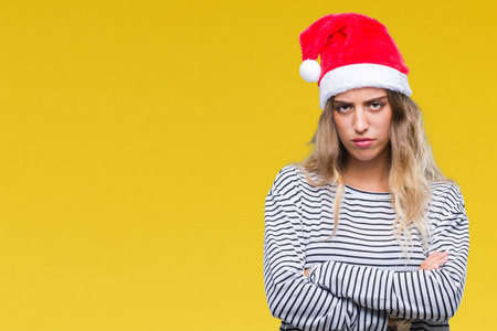 美丽的年轻金发女人戴着圣诞帽，在孤立的背景怀疑和紧张的不赞成的表情在脸上交叉的手臂。 消极的人。