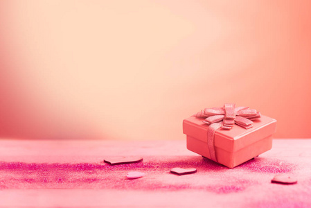 红色礼品盒和心形，粉红色桌子上有镀金。 爱情观念和情人节