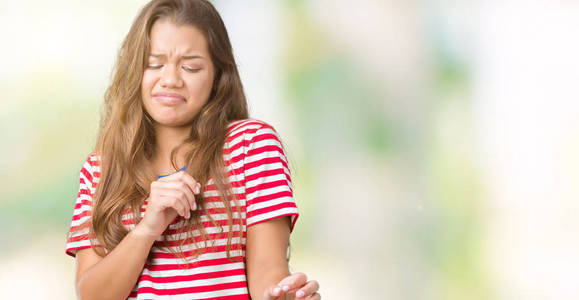 年轻漂亮的黑发女人穿着条纹T恤在孤立的背景上，厌恶的表情，不高兴和恐惧的做厌恶的脸，因为厌恶的反应。 举起双手。 令人讨厌的概念