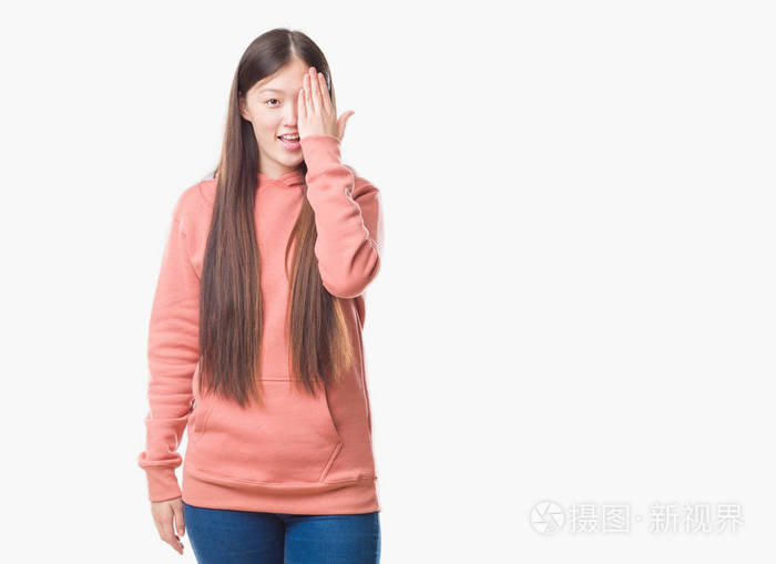 年轻的中国女性,穿着运动运动衫,用手遮住一只眼睛,脸上带着自信的