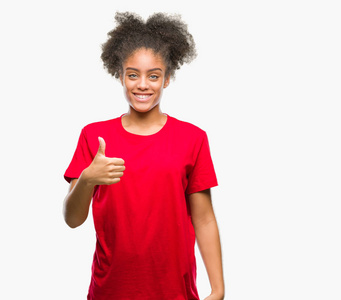 年轻的美国黑人妇女，在孤独的背景下，用手做快乐的竖起大拇指的手势。赞许的表情看着相机，显示出成功。