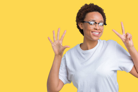 美丽的年轻非洲裔美国妇女戴着眼镜，在孤立的背景上，用手指第七，同时微笑，自信和快乐。