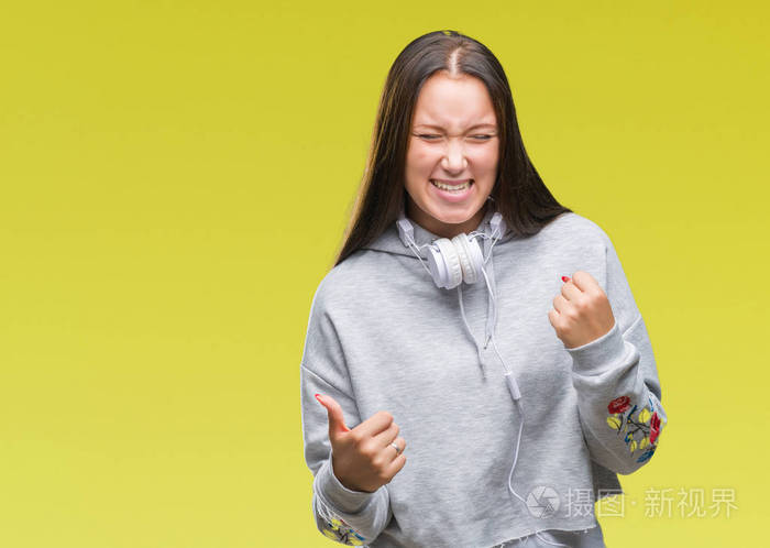 年轻美丽的高加索学生妇女戴着耳机,在孤立的背景下,非常高兴和兴奋地