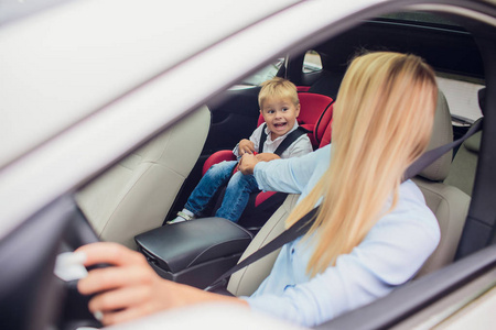 特写镜头妈妈开车, 系好安全带.儿子在后座上家人竖起大拇指照片