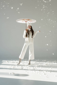穿着时髦的冬衫围巾站在日本伞下白雪皑皑的快乐女人