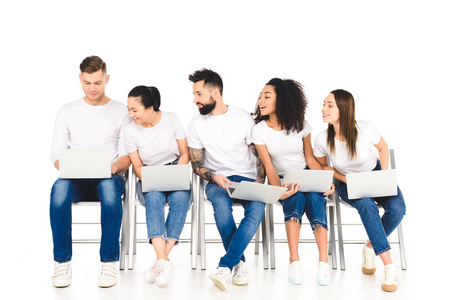 多文化好奇的年轻人看着孤立在白色上的笔记本电脑