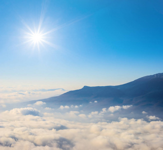 在闪耀的阳光下,被浓密的云层覆盖的山脊照片