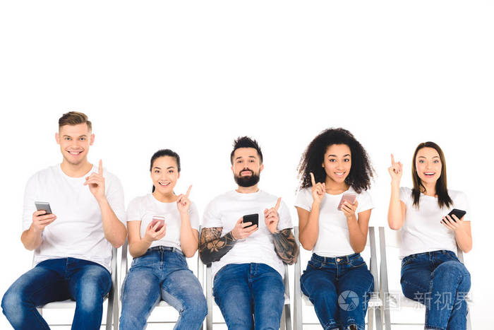 多文化的年轻人群体使用智能手机并在白色上显示出孤立的想法标志