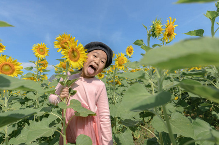 可爱的亚洲女孩在农场里笑着向日葵,快乐的生活理念照片