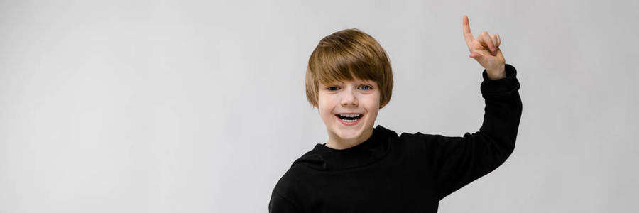 可爱的小快乐微笑的男孩的肖像站在工作室显示在空白区域在灰色背景