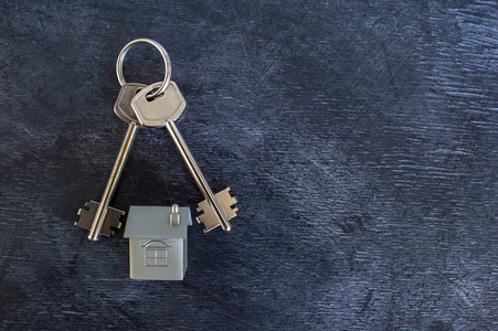 一堆钥匙躺在老式的黑暗背景上,以及以金属布局的形式模仿房子.