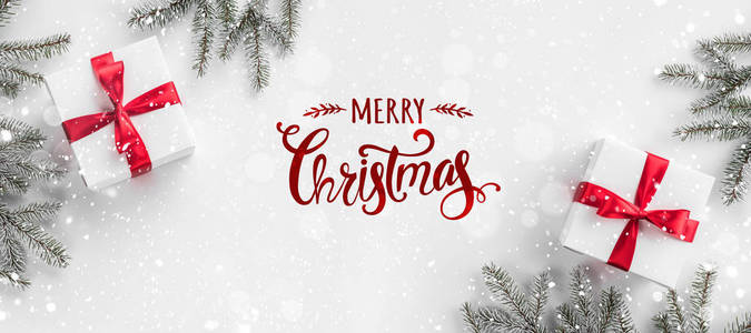 圣诞快乐印刷在白色背景与礼品盒冷杉枝红色装饰。 圣诞节和新年卡雪花。 平躺式顶部视图