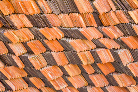 抽象的堆和一包新的粘土瓷砖，以覆盖佛教寺庙的屋顶。 在建筑施工现场堆放新的橙色屋顶瓷砖作为背景。
