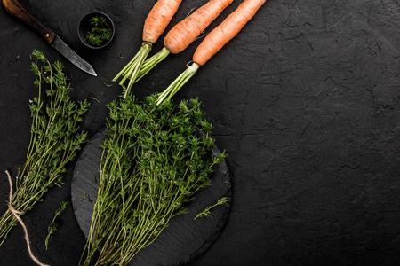 健康的生夏素食蔬菜胡萝卜和草本百里香在暗石背景。 健康食品烹饪清洁饮食俯视图平视图复制