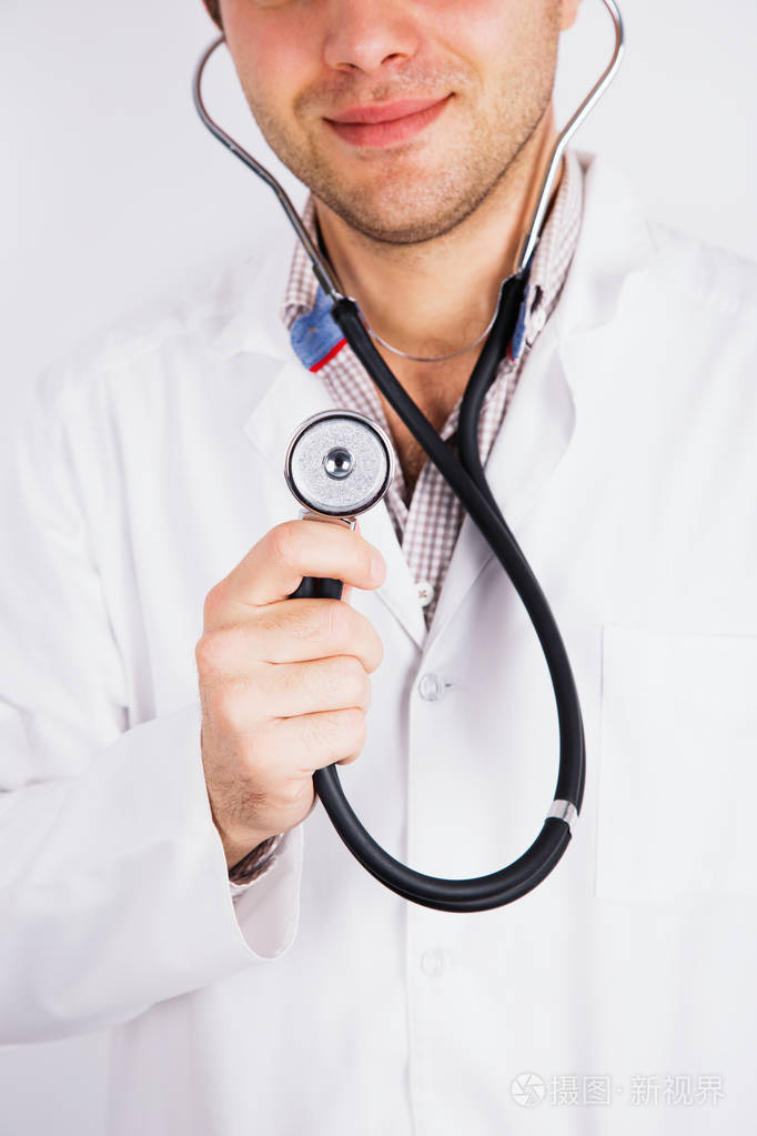 粗暴微笑的男医生穿着白色长袍,手里拿着听筒.