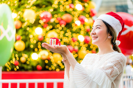 微笑美丽的亚洲年轻女子的肖像，带着礼物在节日圣诞博览会上，老式效果过滤器。