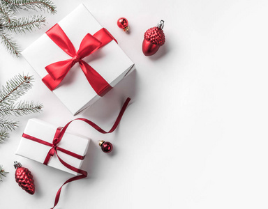 创意框架由圣诞杉枝在白纸背景上与红色装饰松果礼品盒。 圣诞节和新年主题。 平躺式顶部视图