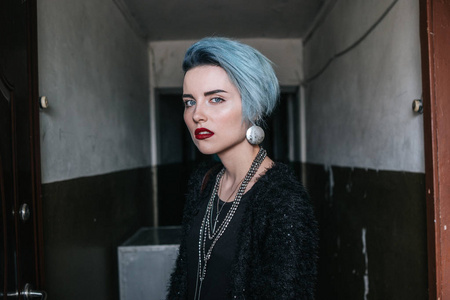 这位留着蓝色时髦发型的女孩站在乌克兰的一条旧走廊里看着镜头