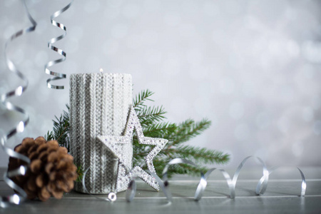 银色圣诞新年蜡烛与卷曲彩带蝴蝶结装饰在闪闪发光的Bokeh灯背景与文本复制空间。