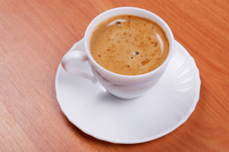 白色美丽的瓷杯新鲜准备的咖啡与茶托在木制桌子顶部的视图。