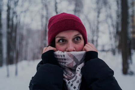 这个女孩在冬天的树林里休息。 在冬天的公园里，年轻的女人在雪地里散步