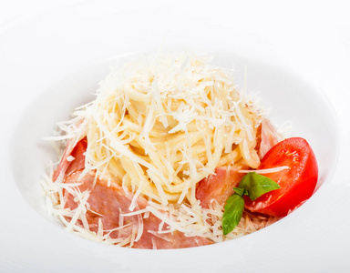 在清淡的木制背景意大利菜肴上，在盘子上放着肉火腿帕尔马干酪罗勒和番茄。 餐桌上的配料