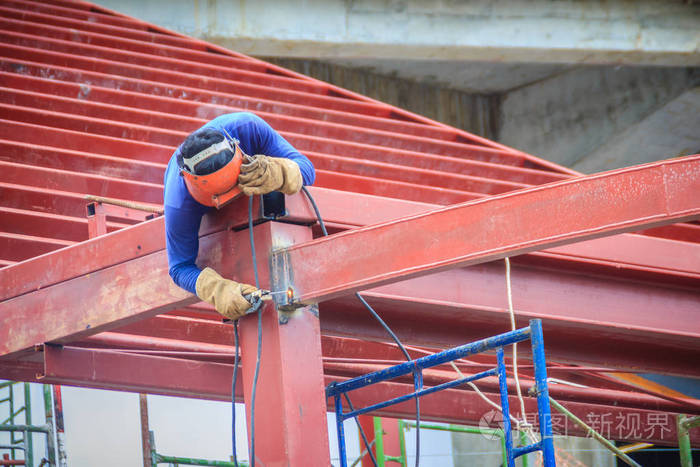 冒险焊工在建筑物施工现场的钢屋面结构顶部攀爬和焊接.
