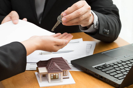 妇女从房地产经纪人那里拿钥匙,并在签订租赁合同,贷款购买协议后讨论