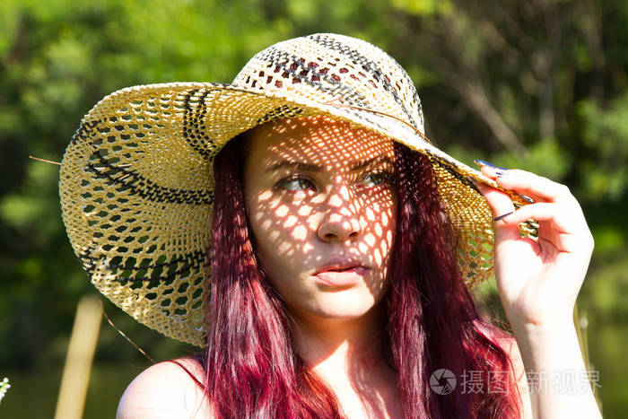 在灿烂的夏日阳光下戴着草帽的女孩