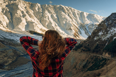 时髦的年轻女孩带着背包在雾山峰上享受日落。 游客背景视图模型。 徒步旅行者在旅途中寻找阳光