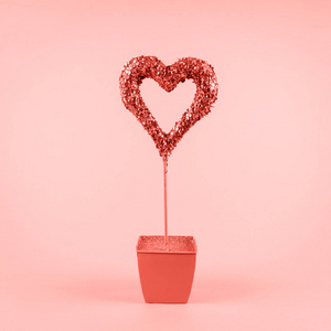 粉红色背景上花盆里闪闪发光的心。 情人节和爱的成长理念。 正方形。 活珊瑚主题颜色2019年
