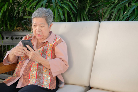 年长的女人拿着手机惊讶地听到消息。 老年女性用手机应用短信。 亚洲高级使用智能手机在线社交网络连接