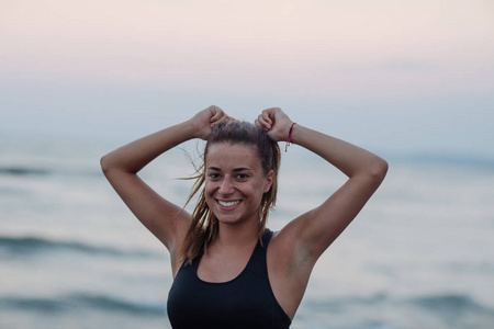 美丽的高加索微笑的女运动员站在海边。