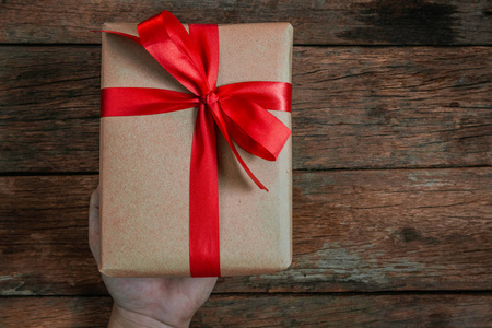 奖金人类手赠礼物棕色礼盒蝴蝶结红色带旧木地板顶景圣诞快乐新年理念