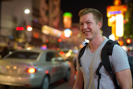 年轻快乐的旅游人背包客晚上在唐人街街头思考