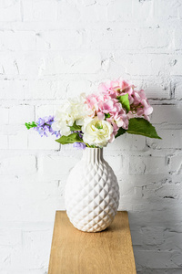 美丽的花束放在乡村木架上的白色陶瓷花瓶里
