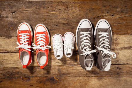 在甜蜜的家快乐的家庭养育和生活方式概念中，不同尺寸的老式木地板上父亲母亲和儿子女儿家庭的胶鞋运动鞋的概念形象。