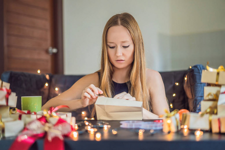 年轻女子在餐桌上用手工纸包装圣诞礼物。