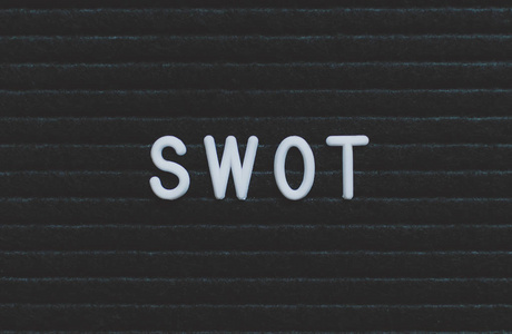 写在信板上的单词SWOT。 黑色背景上的白色字母。 业务概念