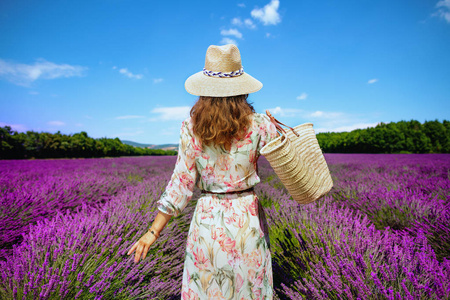 的女人穿着草袋,在五彩缤纷,生机勃勃的薰衣草长廊上悠闲地散步照片
