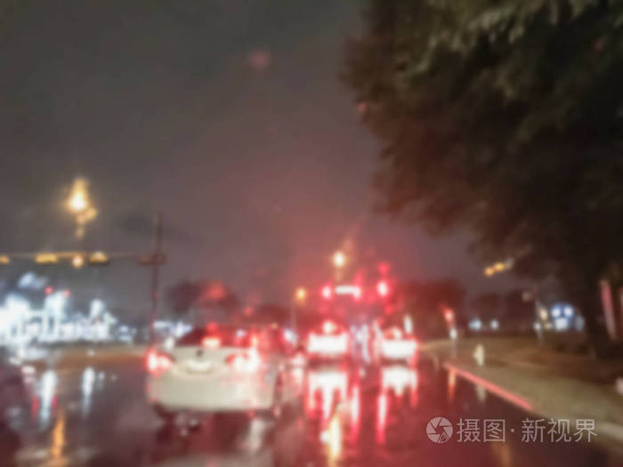 模糊抽象停车车在红绿灯路口和后灯反射在雨天沥青道路上.