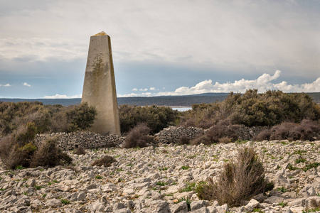 春天阴天的克雷斯岛上的旧混凝土三角柱蓬松的灰色云