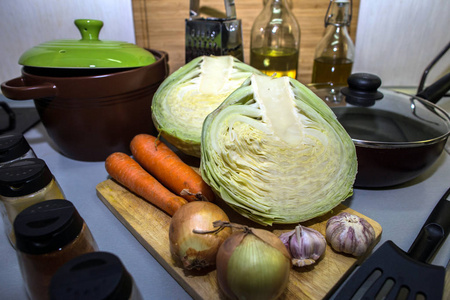 在平底锅中煮素汤的新鲜原料。 卷心菜胡萝卜洋葱和大蒜在锅和锅的背景上。