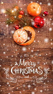 圣诞装饰与杉树枝和橘子在木制背景与雪模糊的火花发光和文字快乐的圣诞节和新年。 圣诞卡