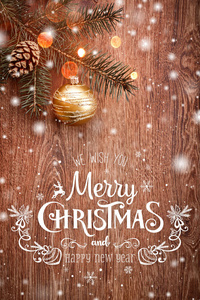 圣诞装饰与杉树枝在木制背景与雪模糊的火花发光和文字快乐的圣诞节和新年快乐。 圣诞卡