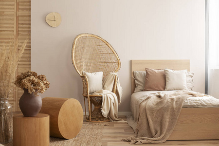 孔雀椅，旁边有枕头和毯子，单人床有米色床上用品和温暖的毯子，真照片