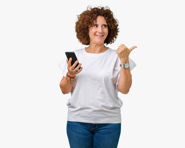 中老年女性使用智能手机并发短信，背景是孤立的，用拇指指向侧面，脸上洋溢着幸福的笑容