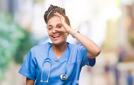 年轻的辫子非裔美国女孩专业外科医生在孤立的背景下做好手势，用手微笑的眼睛透过手指看着快乐的脸。